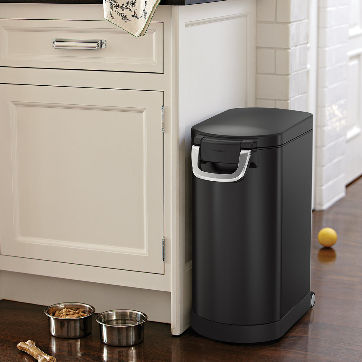 Angled view of Simplehuman Matte Black Large Pet Food Can, closed securely in kitchen setting, airtight locking handle.