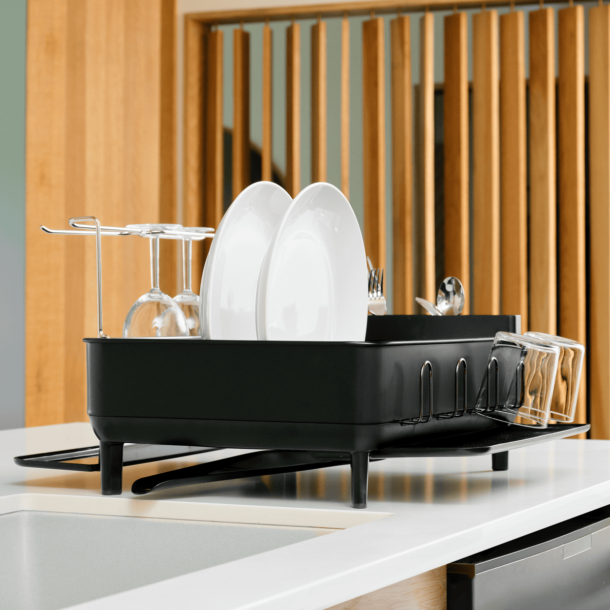 Angled view of Simplehuman Matte Black Steel Frame Dishrack, showing wine glass rack and integrated drying space on a white countertop.