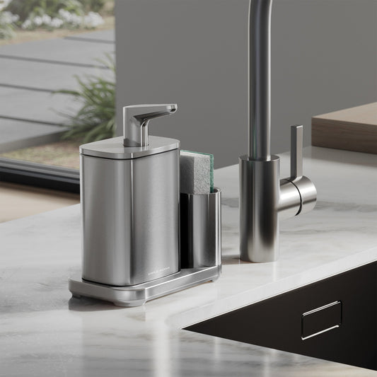 Simplehuman Brushed Pulse Pump with Caddy on kitchen sink edge, sponge in caddy on marble countertop.