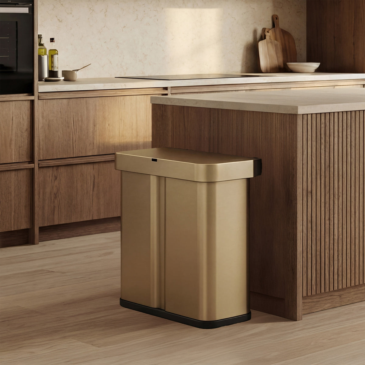 Simplehuman's Matte Gold Sensor Recycler featured in an elevated kitchen setting featured mainly with wood and marble.